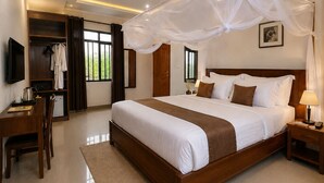Una habitación de hotel con una cama grande, un escritorio, un armario y un televisor.