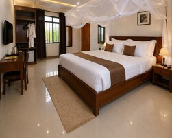 A hotel room with a large bed, a desk, a wardrobe, and a TV.