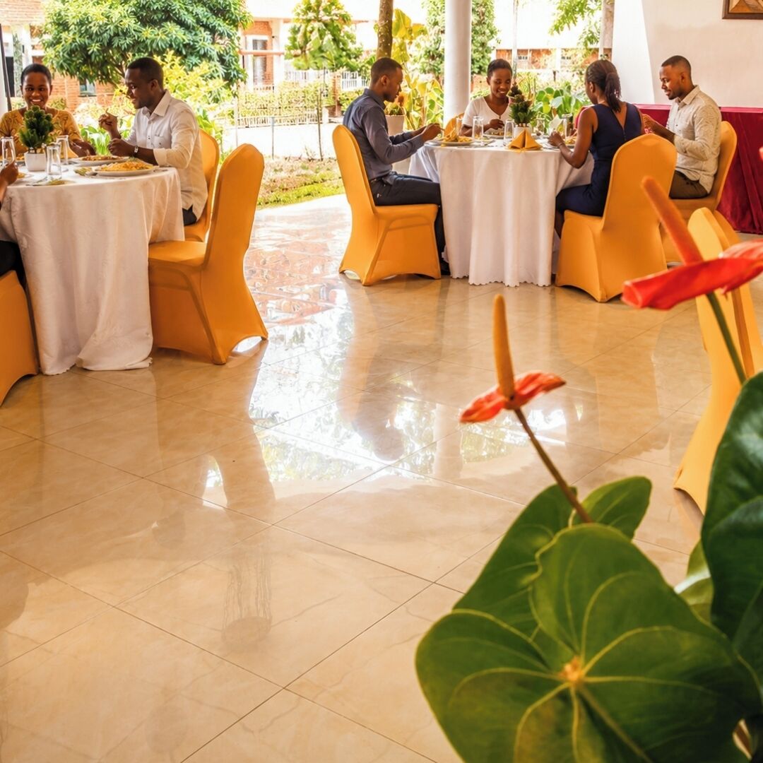 Un comedor con mesas redondas, sillas amarillas y piso de baldosas.