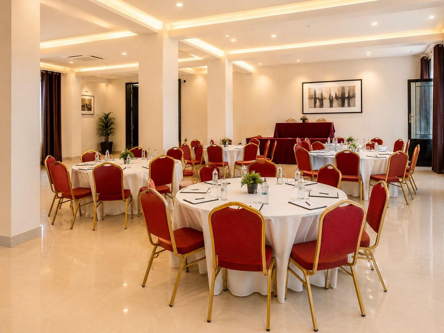 A conference room with round tables, red chairs, and a stage.