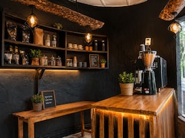 A coffee shop interior with shelves of coffee bags, a coffee machine, and a menu board.