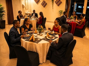 A formal dining room with round tables, chairs, and guests seated for a meal.