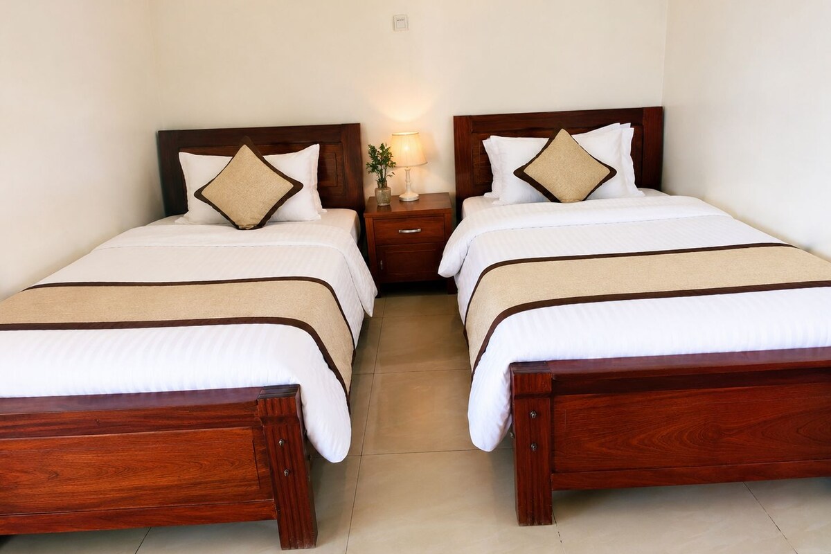 A double bed with a wooden frame, two bedside tables, a nightstand, and a lamp.