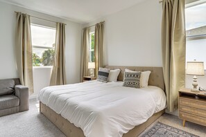 A bedroom with a large bed, two bedside tables, a chair, and curtains. - Epic Everglades & Florida Keys Adventure Basecamp (Homestead)