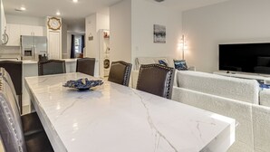 Un salon moderne avec un coin repas, un téléviseur et une cuisine en arrière-plan.