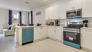 Une cuisine moderne avec des meubles blancs, un lave-vaisselle, une cuisinière et un four à micro-ondes.