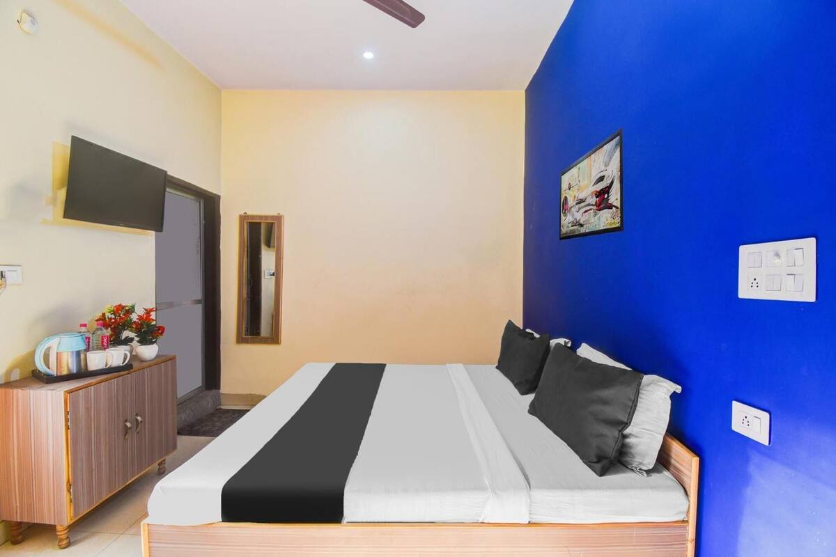 Ein Schlafzimmer mit einem Bett, einer Kommode, einem Spiegel und einem Wandbild.