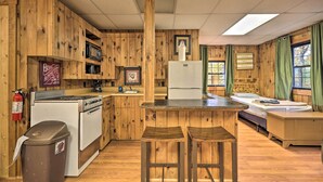 A cabin-style kitchen with wooden walls, a stove, a refrigerator, and a bar area with stools. - Near Raystown Lake! 3 Units at Urban Saddle Ranch (Huntingdon)