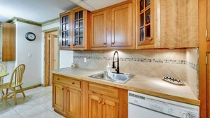 A kitchen with wooden cabinets, a stainless steel sink, and a dishwasher. - Classic Up North Cabin: Boat, Fish, ATV & Explore (Harrison)