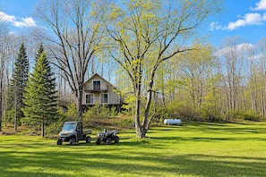 A house with a large yard, surrounded by trees and a clear sky.