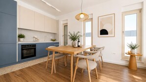 Une cuisine moderne avec un coin repas, un plancher en bois et une grande fenêtre.