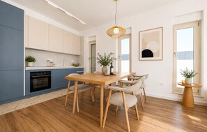 A modern kitchen with a dining area, wooden flooring, and a large window. - Awesome home in Smokovic with sauna (Smokovic)