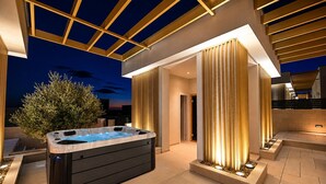 Un espace moderne aménagé à l’extérieur avec un jacuzzi, une pergola, un grand arbre et une entrée bien éclairée.
