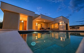 Een modern huis met zwembad, grote ramen en een terras.