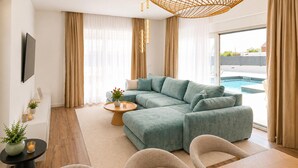 Un salon moderne avec un canapé d’angle, une table basse et une vue sur une piscine.