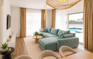 A modern living room with a sectional sofa, a coffee table, and a view of a swimming pool. - Awesome home in Smokovic with sauna (Smokovic)