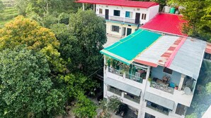 Un edificio de varios pisos con techo rojo, toldo verde y un balcón.
