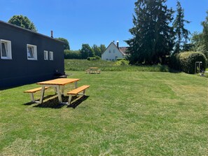 Un espace extérieur verdoyant avec des tables de pique-nique et un bâtiment en arrière-plan.
