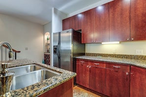 A kitchen with granite countertops, stainless steel appliances, and wooden cabinets. - Walkable EaDo Condo Near Dtwn: Modern + Chic! (Houston)