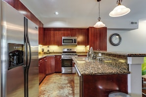 A modern kitchen with stainless steel appliances, granite countertops, and wooden cabinets. - Walkable EaDo Condo Near Dtwn: Modern + Chic! (Houston)