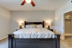 Une chambre à coucher avec un lit, deux lampes de chevet, un ventilateur de plafond et un placard.