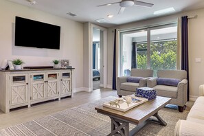 A modern living room with a flat-screen TV, a sofa, a coffee table, and a large window. - Work & Play! Home w/ Modern Comfort in Estero (Estero)