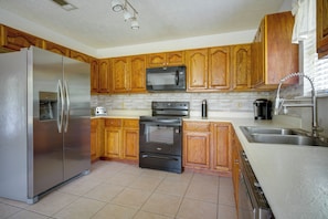 A kitchen with wooden cabinets, a stainless steel refrigerator, a microwave, an oven, and a dishwasher.