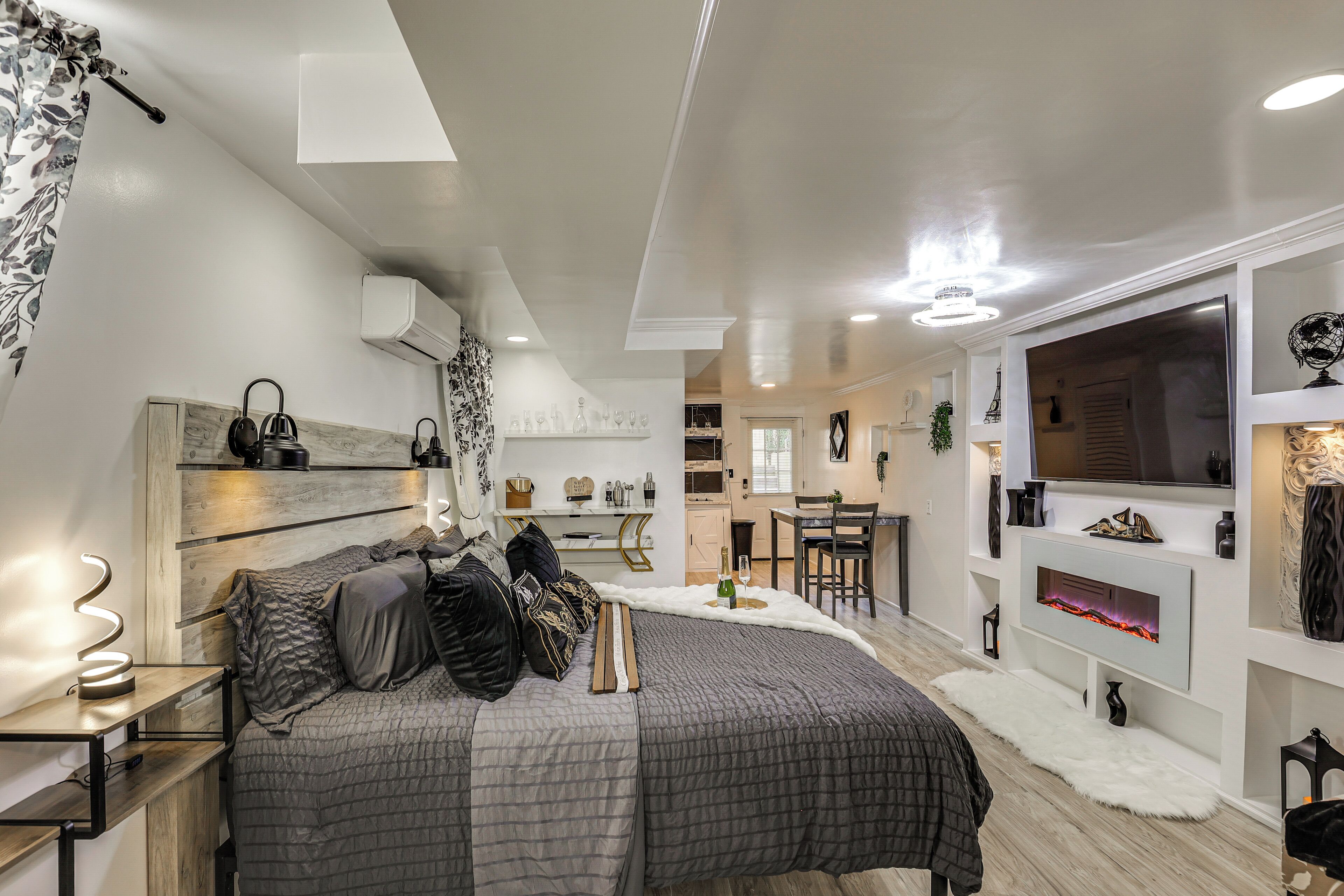 Quarto moderno com cama, mesa de cabeceira e televisão.
