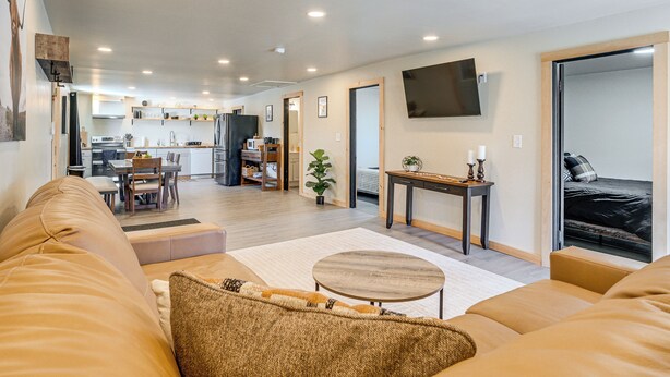 A modern living room with a sofa, a small round table, and a kitchen in the background.