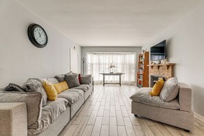 Ein Wohnzimmer mit zwei Sofas, einer Uhr, einem Kamin und einem Fernseher.