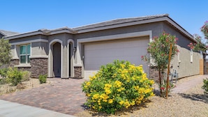A residential house with a garage, stone foundation, and a well-maintained garden with yellow flowers. - 9 Mi to Las Vegas Strip! Spacious Single-Story Gem (Las Vegas)