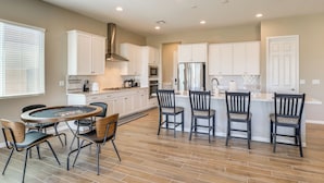 A modern kitchen with white cabinets, a central island with bar stools, a dining table with chairs, and a built-in stove. - 9 Mi to Las Vegas Strip! Spacious Single-Story Gem (Las Vegas)