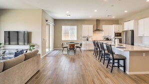 A modern kitchen with white cabinets, a dining area with a round table, and a living room with a sofa. - 9 Mi to Las Vegas Strip! Spacious Single-Story Gem (Las Vegas)