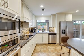 A modern kitchen with stainless steel appliances, a large window, and a view of the backyard. - Sleek Family Home w/ Backyard Oasis in San Diego! (San Diego)
