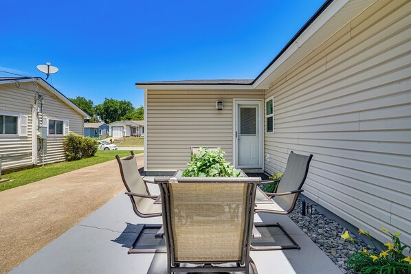 A patio with a table and chairs, a small shed, and a house with a door and window. - 2 Mi to Stadiums & UT Arlington! Stylish Home (Arlington)