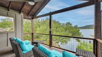 Un espace extérieur abrité, aménagé avec des meubles en osier et offrant une vue sur un lac.