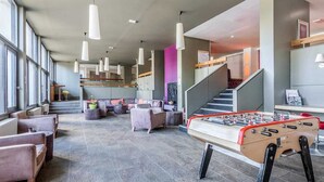 A spacious lobby with seating, a foosball table, and a staircase. - Résidence Pierre & Vacances Mountain view (Flaine)