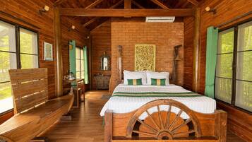 Un dormitorio de estilo cabaña de madera con cama, banca, cómoda y ventanas amplias.
