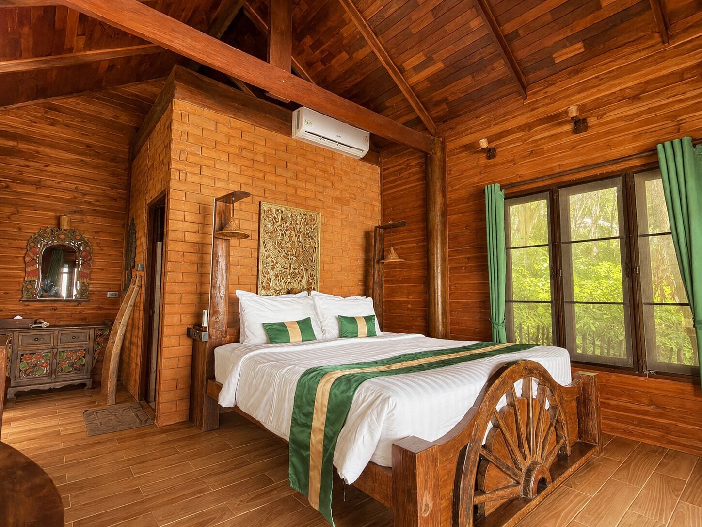 Un dormitorio de cabaña de madera con una cama, un aparador, un espejo y una ventana con cortinas.