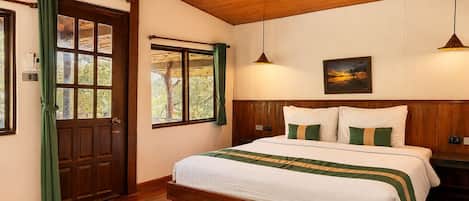 A bedroom with a wooden ceiling, a large bed with white bedding and green accents, a window with curtains, and a painting on the wall.