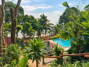 A pool surrounded by tropical vegetation and a wooden deck. - Ting Rai Bay Resort (Nuea Khlong)