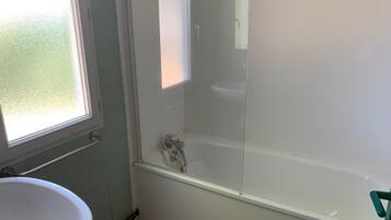 Un baño con bañera, ventana y lavabo.