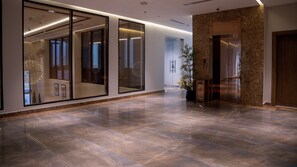 A spacious lobby with a marble floor, large glass doors, and a modern elevator.