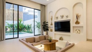Uma sala de estar moderna com um sofá grande, uma mesa de centro e uma televisão presa à parede.
