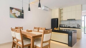 Uma cozinha moderna com ilha central, mesa de jantar de madeira com cadeiras e iluminação pendente.