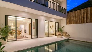 Uma casa moderna com piscina, portas de vidro que dão para uma sala de jantar e uma varanda.
