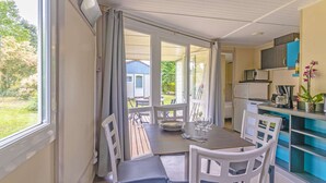 Een eetgedeelte met een tafel voor vier personen, een keuken met moderne apparatuur en uitzicht op de achtertuin.