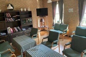 A furnished room with a television, seating area, and a bookshelf.