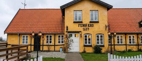 A yellow building with the sign 'FEMØ KRO 1659' and a red-tiled roof.