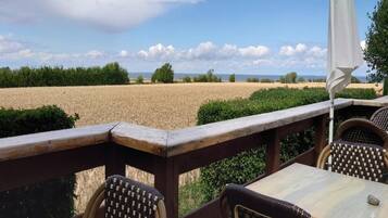 A wooden deck with a table and chairs overlooking a field.